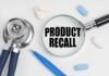 Stethoscope, pills, pen, magnifying glass with Product Recall.