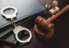 Gavel and handcuffs on a desk.