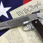 Gun on U.S. Constitution with American flag background.