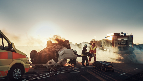 Firefighters responding to a car crash at sunset.