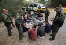 Border patrol agents detaining a group of immigrants.