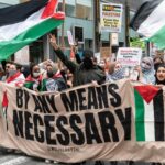 Pro-Palestine protest with banners and flags in city street.