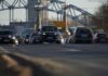 Cars driving on a road with bridge background.