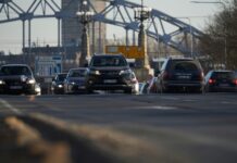 Cars driving on a road with bridge background.