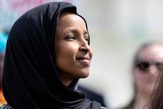 1369298648 A woman wearing a black hijab looking thoughtfully into the distance