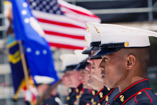 shutterstock_355868381.jpg Marines in uniform stand at attention with American flag.