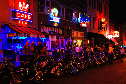 shutterstock_1159755856.jpg Vibrant street scene at night with neon signs and parked motorcycles