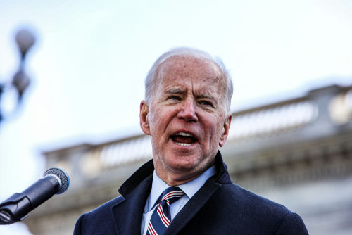 A man speaks into a microphone outdoors.