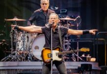 Springsteen’s Bold Move SPARKS White House Clash A guitarist performing passionately on stage with a drummer in the background
