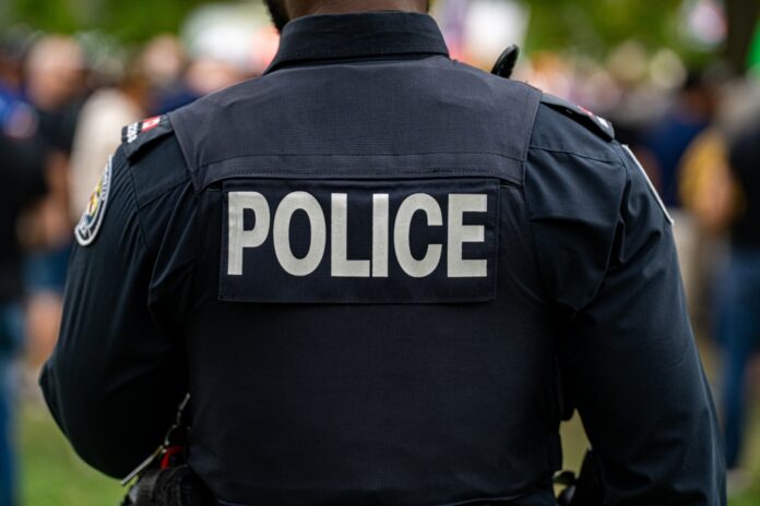 shutterstock_2678017741.jpg Back view of a police officer in uniform at a public event