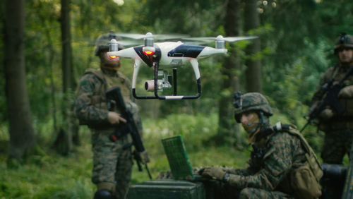 shutterstock_761939488 Soldiers in a forest operating a drone.