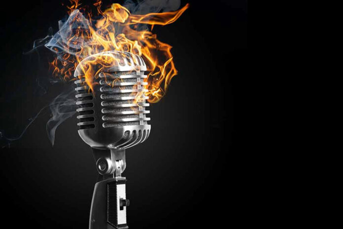 1849990897 Vintage microphone with flames and smoke.