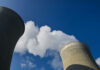 Cooling towers emitting steam under a clear blue sky.