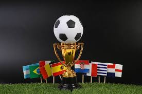 images-27- A golden soccer trophy with a black and white ball on top, surrounded by small flags of various countries