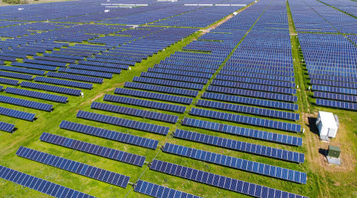 shutterstock_1046816461 Aerial view of an expansive solar panel farm.