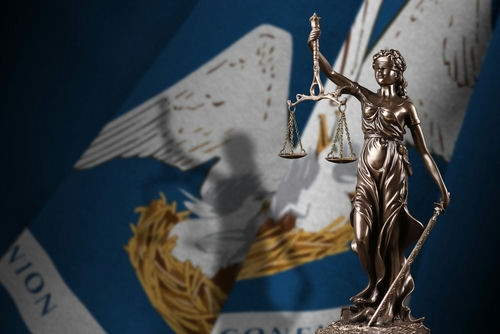 shutterstock_2220126031 Lady Justice statue with Louisiana state flag background.