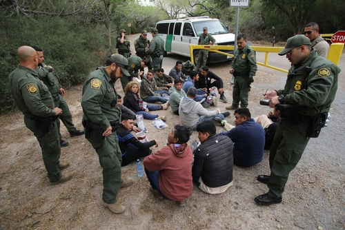Border patrol agents detaining a group of immigrants.