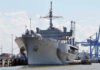 Texas Bets Big: $3.2B Robot Shipyard Large naval ship docked at an industrial port.