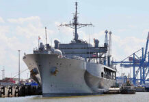 Texas Bets Big: $3.2B Robot Shipyard Large naval ship docked at an industrial port.