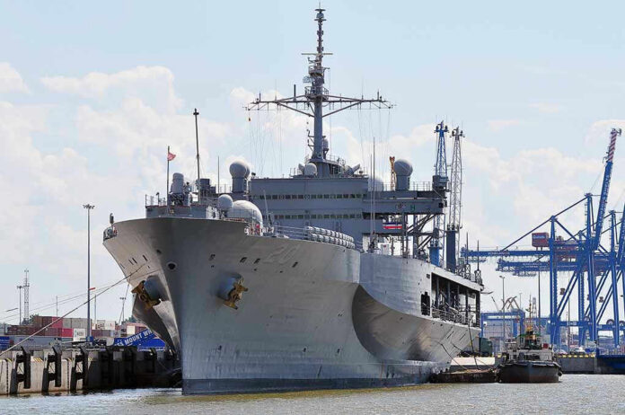 452352514 Large naval ship docked at an industrial port.