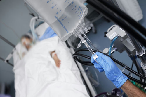shutterstock747471982-1jpg Patient in hospital bed with IV drip close-up.