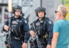 Two armed police officers engaging with a man outside.