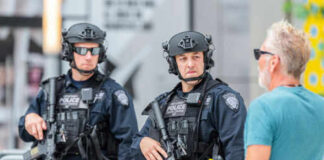 Two armed police officers engaging with a man outside.