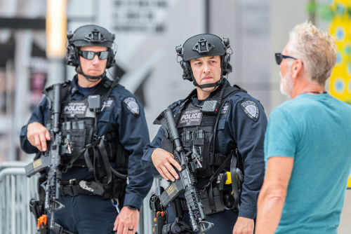 shutterstock_1554210416 Two armed police officers engaging with a man outside.