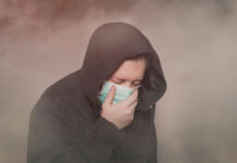 Toxic Orange Sky Slams Toronto Person with hood and mask coughing in foggy setting.