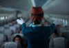 Flight attendant giving safety demonstration in airplane aisle