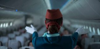 Flight attendant giving safety demonstration in airplane aisle