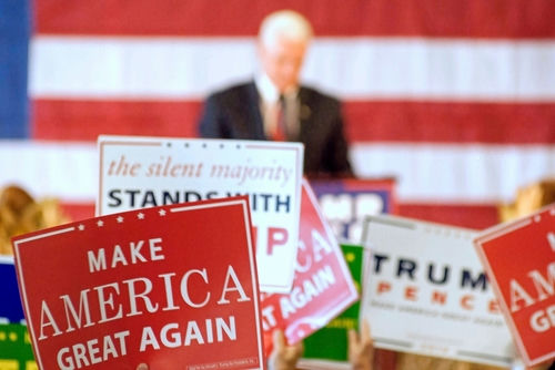 shutterstock_2185750739 political rally with speaker and campaign signs in front of an American flag